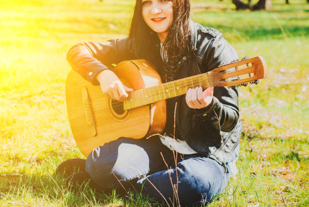 istock woman playing an acoustic guitar black 947771506