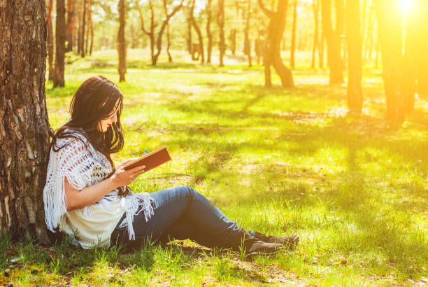 istock Woman relaxing reading book at park 947776318