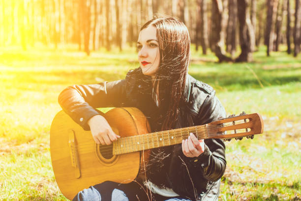 istock woman playing an acoustic guitar black 947776544