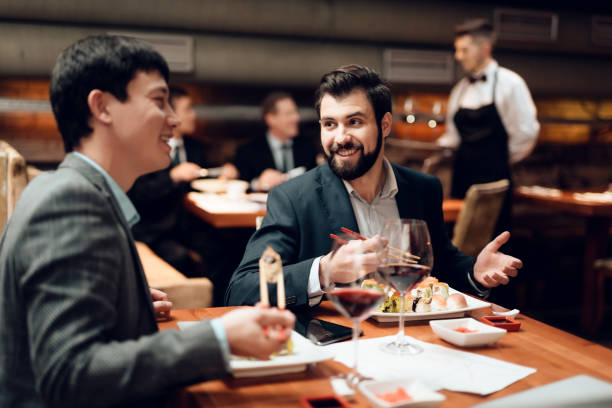 Meeting with chinese businessmen in restaurant. Two men are eating sushi. stock photo