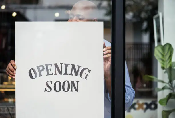 Photo of Man putting on store opening soon sign