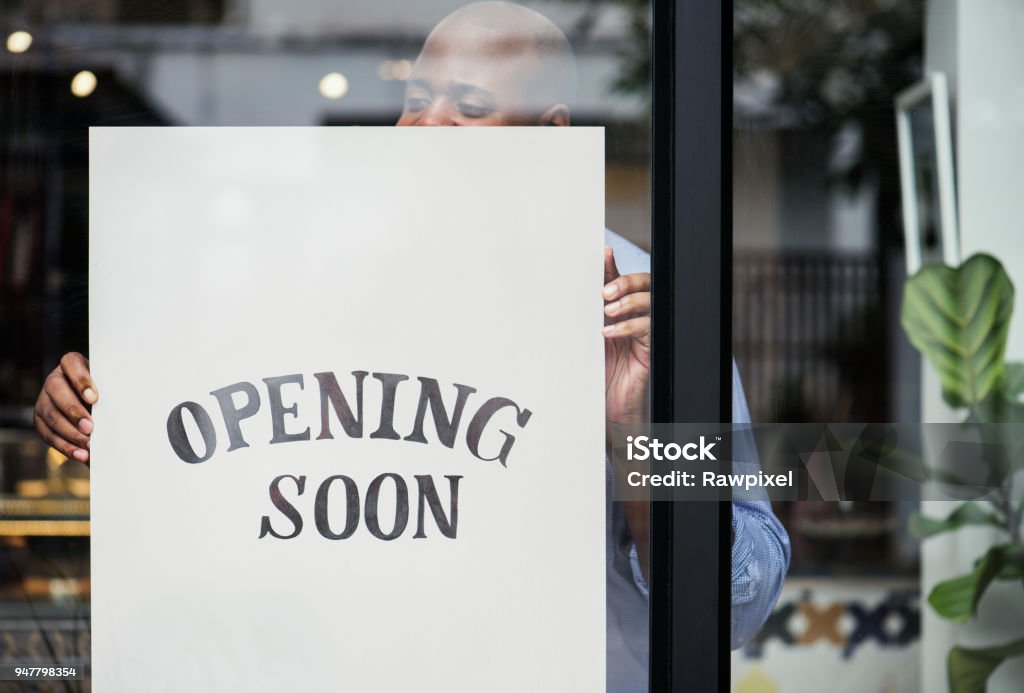 Homem colocando na abertura em breve sinal loja - Foto de stock de Loja royalty-free