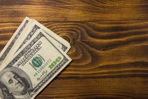istock One hundred dollars bills on wooden desk 947799088