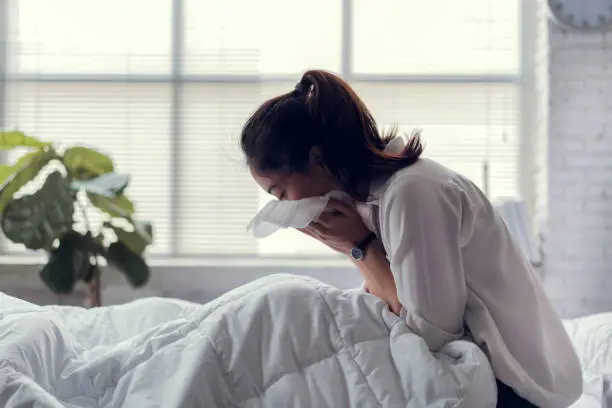 Photo of The businessman is unable to work, she is sick and sneezing heavily in bed.