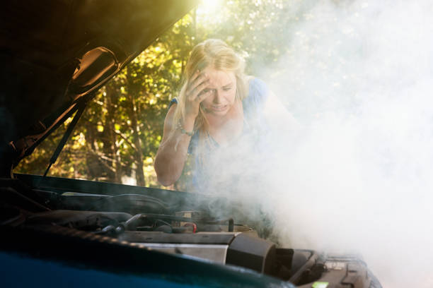 Smoke pours from young woman's car engine