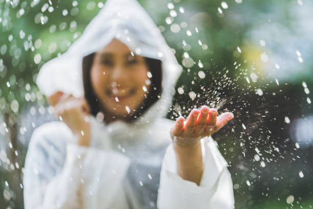 アウトドア レインコートを着て雨の日のアジア女性。彼女は幸せです。彼女は雨に触れないように使用されます。 - umbrella women storm yellow ストックフォトと画像