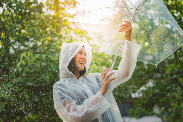 deszczowy dzień azjatka ubrana w płaszcz przeciwdeszczowy na świeżym powietrzu. jest szczęśliwa. - parasol umbrella asian ethnicity asian culture zdjęcia i obrazy z banku zdjęć
