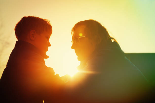 istock father and son silhouettes at sunset, parenting concept 947812080