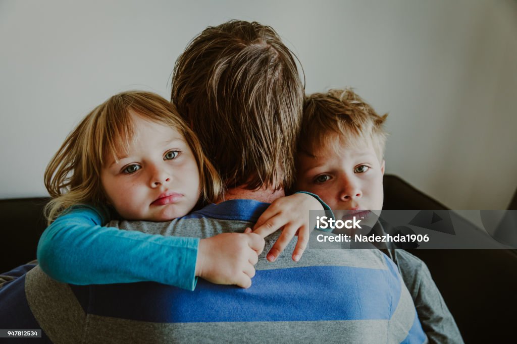 sad little boy and girl hugging father, family in sorrow sad kids hugging father, family in sorrow, loss and pain concept Sadness Stock Photo