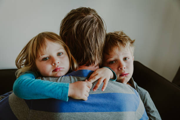 sad little boy and girl hugging father, family in sorrow sad kids hugging father, family in sorrow, loss and pain concept child sadness stock pictures, royalty-free photos & images
