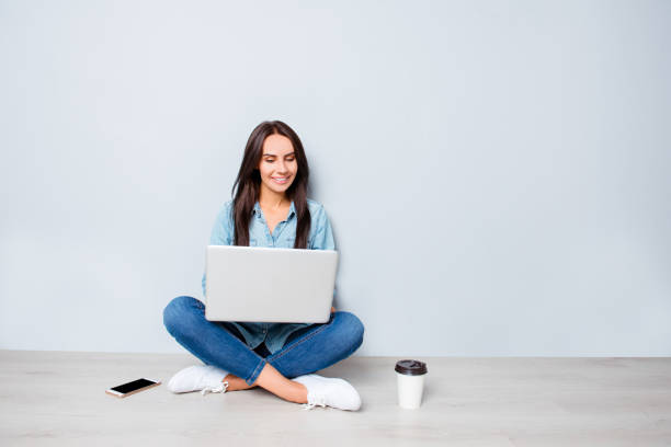 glücklich jungstudentin am boden und tippen auf laptop - floor sitting stock-fotos und bilder