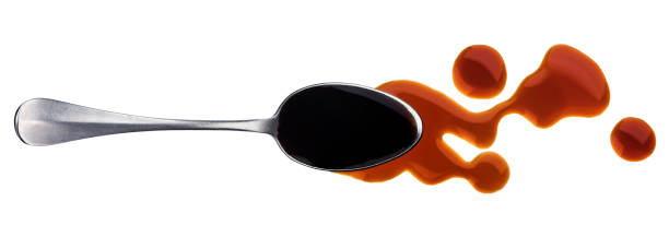 istock Soy sauce. Splashes and spilled soy sauce with spoon isolated on white background. Top view 947826038