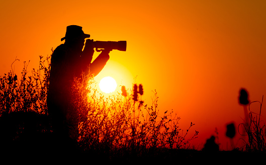 Silhouette of man photographer take photos with sunset background