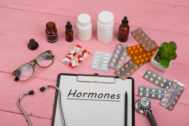 Doctor workplace with clipboard and text "Hormones", medicine bottles, red stethoscope, eyeglasses and pills on pink wooden table. Doctor workplace with clipboard and text "Hormones", medicine bottles, red stethoscope, eyeglasses and pills on pink wooden table. Medication prescription. Health care or illness oestrogen stock pictures, royalty-free photos & images