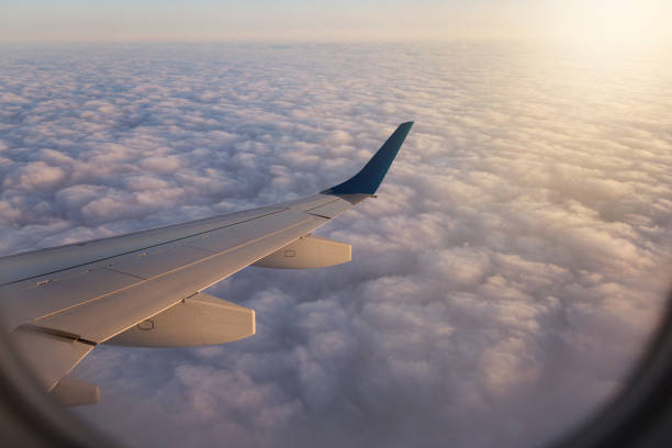 istock above the clouds, view from the airplane, visible wing elements and window frame, concept travel 947838760
