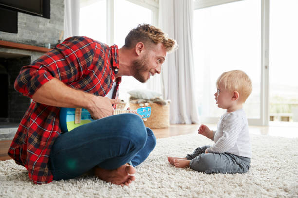 istock Father playing ukulele with young son at home, close up 947844552