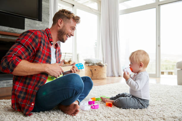istock Father playing ukulele with young son at home, close up 947844596