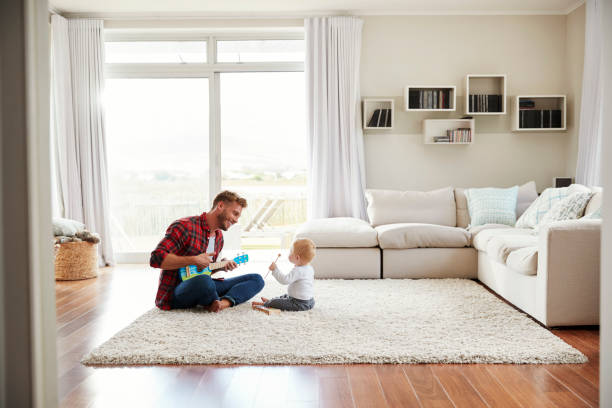 istock Father playing ukulele with young son in their sitting room 947844726