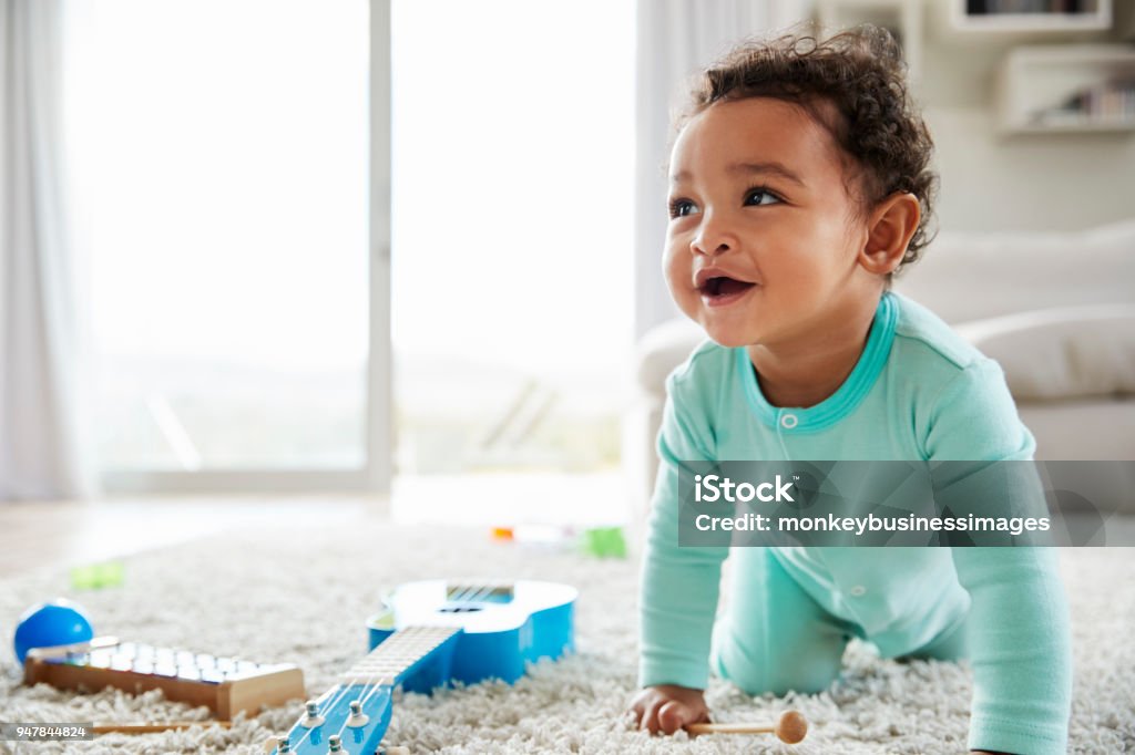 Happy mixed race toddler boy crawling in sitting room Baby - Human Age Stock Photo