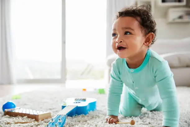 Photo of Happy mixed race toddler boy crawling in sitting room