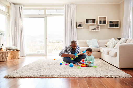 Negro hijo de padre y niño jugando en la sala de estar photo