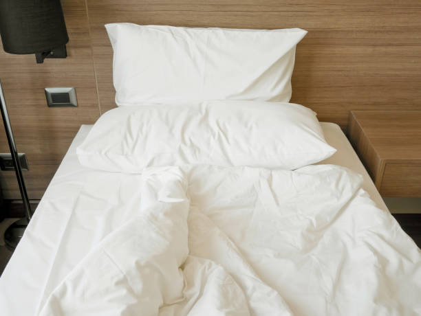 istock Unmade bed with crumpled duvet, bed sheet and pillows 947845382