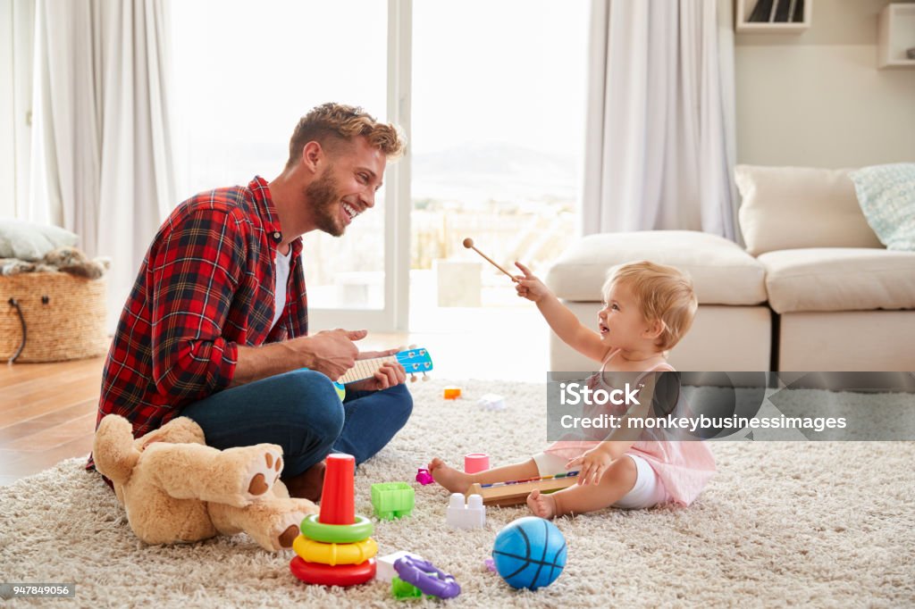 Father and young daughter playing toy instruments at home Father Stock Photo