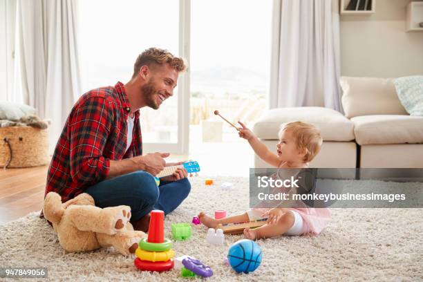 Father And Young Daughter Playing Toy Instruments At Home Stock Photo - Download Image Now