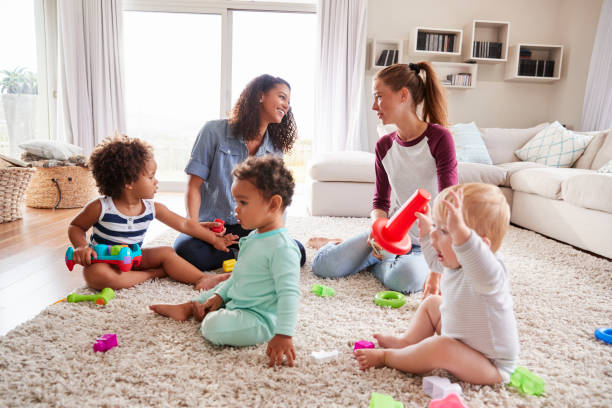 Two friends playing with toddler kids on sitting room floor Two friends playing with toddler kids on sitting room floor group of babies stock pictures, royalty-free photos & images