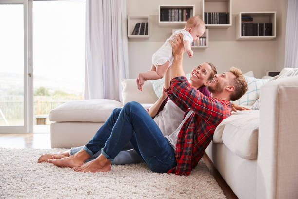 blanco joven pareja jugar con su niño en la sala de estar - three person family fotografías e imágenes de stock