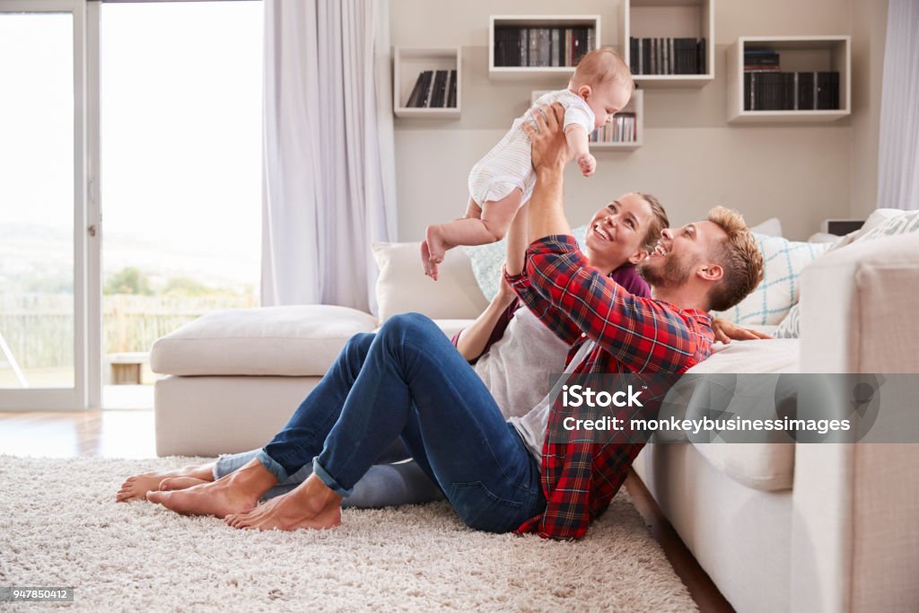 Young white couple play with their toddler in sitting room Family Stock Photo