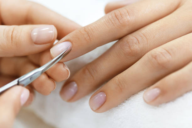istock Manicure. Hands Removing Cuticle From Woman Hand With Scissors 947850436