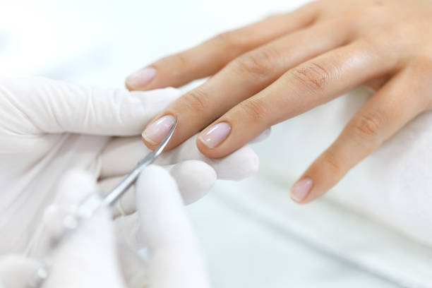 istock Manicure. Hands Removing Cuticle From Woman Hand With Scissors 947850496