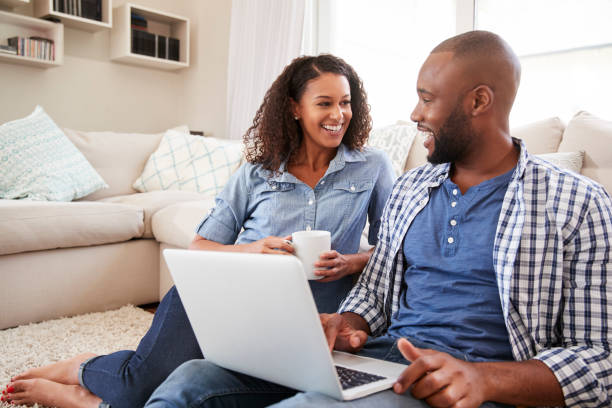Young black couple using laptop at home look at each other Young black couple using laptop at home look at each other face to face stock pictures, royalty-free photos & images