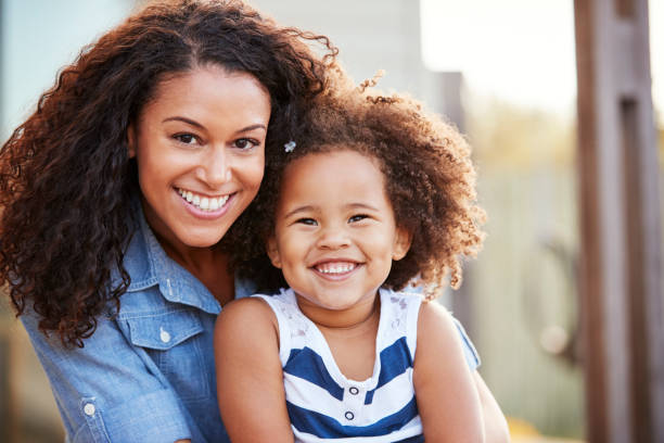 mixed race mother and young daughter smile to camera outside - babies and children close up horizontal looking at camera imagens e fotografias de stock