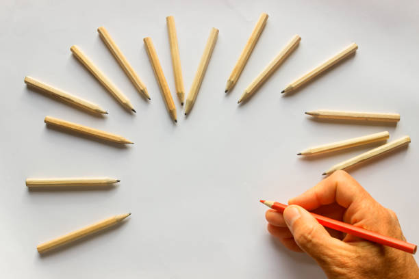 istock Hand holding red pencil. Around plenty identical  pencils .Leadership, uniqueness, independence, initiative, strategy, dissent, think different, business success concept. 947854048