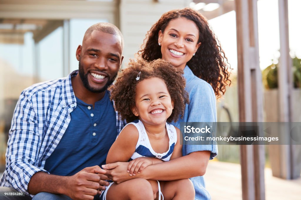 Joven negro familia abrazando al aire libre y sonriendo a cámara - Foto de stock de Familia libre de derechos