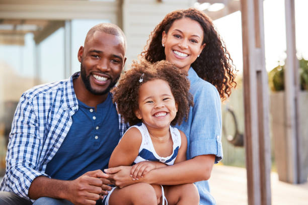 jeune noire famille embrassant à l’extérieur et souriant à la caméra - famille avec un enfant photos et images de collection