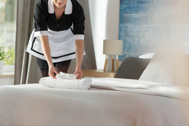 Maid laying fresh towels Young maid laying fresh towels on a bed in hotel room housekeeping staff photos stock pictures, royalty-free photos & images