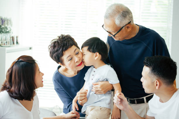 boy kissing grandmother on cheeks with the whole asian family of three generations together at home - human face chinese ethnicity close up men imagens e fotografias de stock