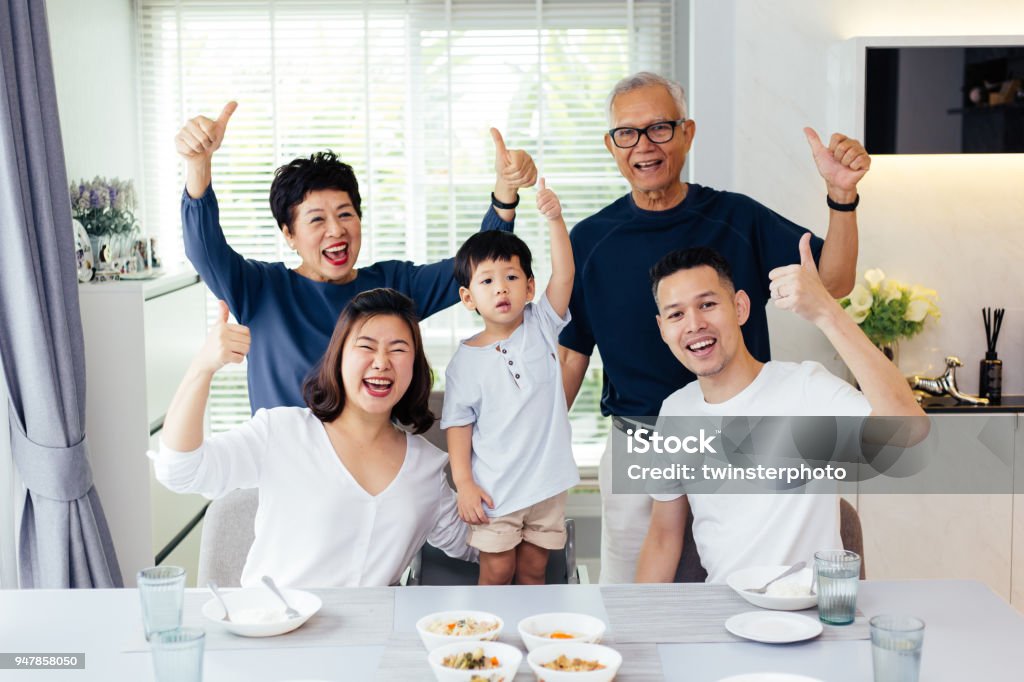 Extended Asian family of three generations having a meal together and showing thumbs up at home with happiness Family Stock Photo