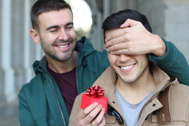 istock Man surprising his boyfriend with a present 947859278