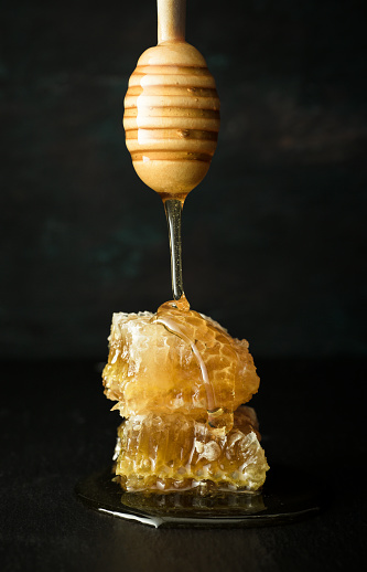 Honey - Wooden spoon with Honeycomb on black ground