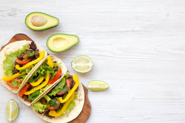 istock Tacos with pork, fresh vegetables, avocado, lime. White wooden background. Top view, flat, overhead. Copy space. 947873676