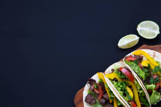 istock Mexican street tacos flat lay composition with beef and vegetables. Dark background. Copy space. Flat top view. 947874334