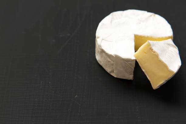 istock Cheese camembert or brie on dark background. Milk production. Side view. Closeup. Copy space. 947874544