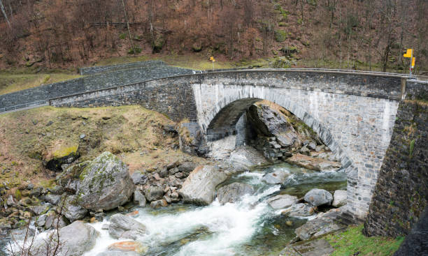 古い石造りの橋のトレイル マーカーと野生の川を渡ると両側にハイキング コース - granite ticino canton switzerland locarno ストックフォトと画像