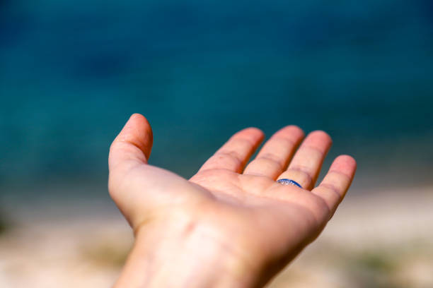 istock Women hand and blue sea 947886524