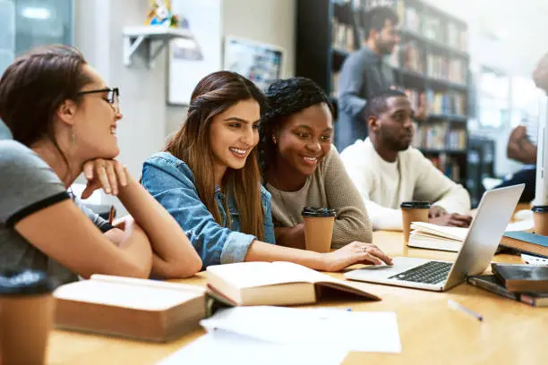 Shot of young women using a laptop together in a college library