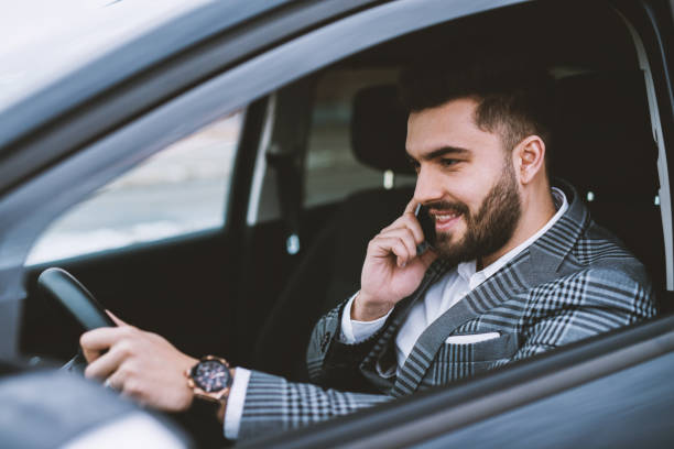 istock Attractive man wearing a suit making a phone call while driving a car in a city. 947918904